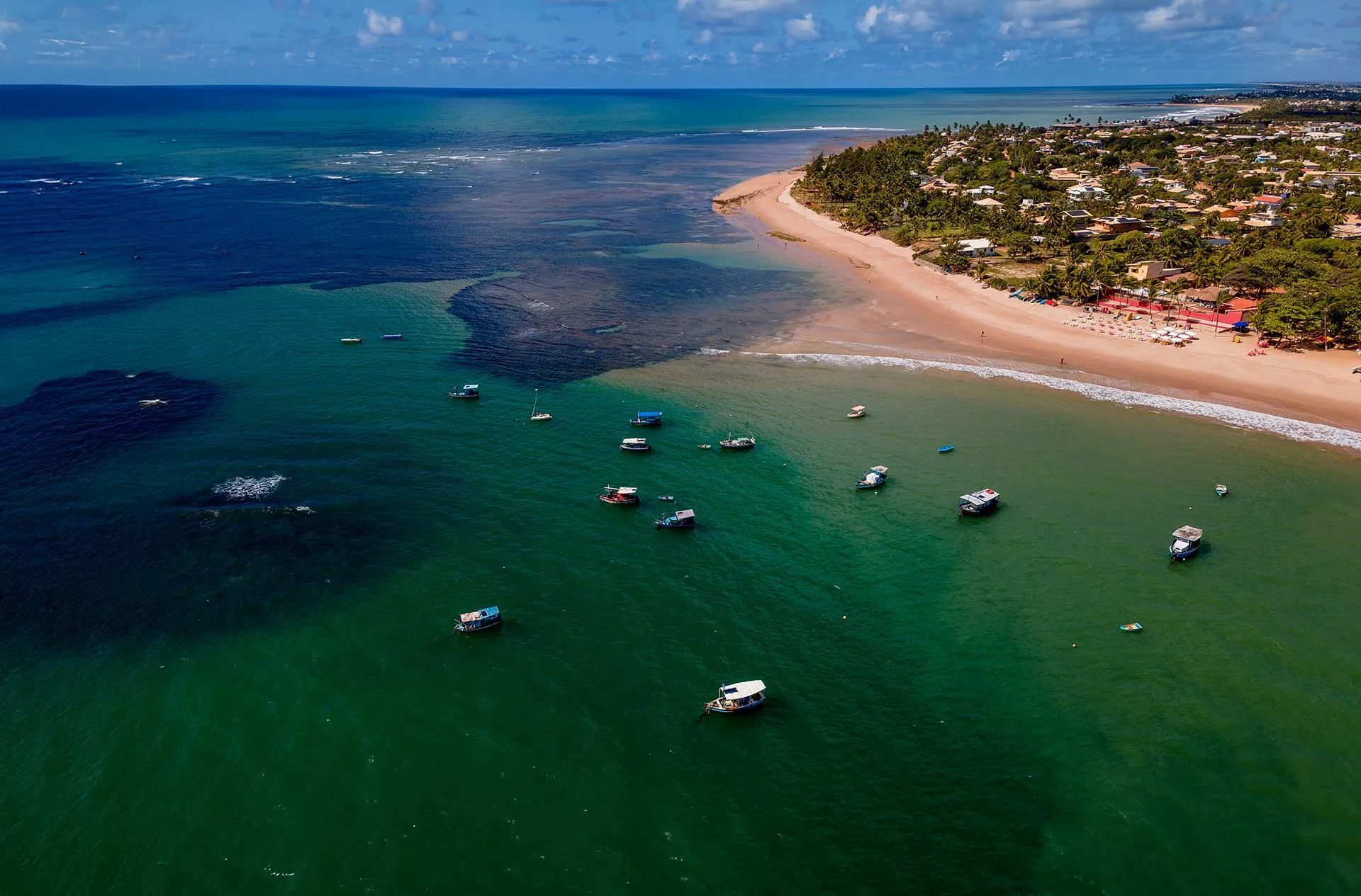 Vista aérea do mar e da orla de Itacimirim com barcos